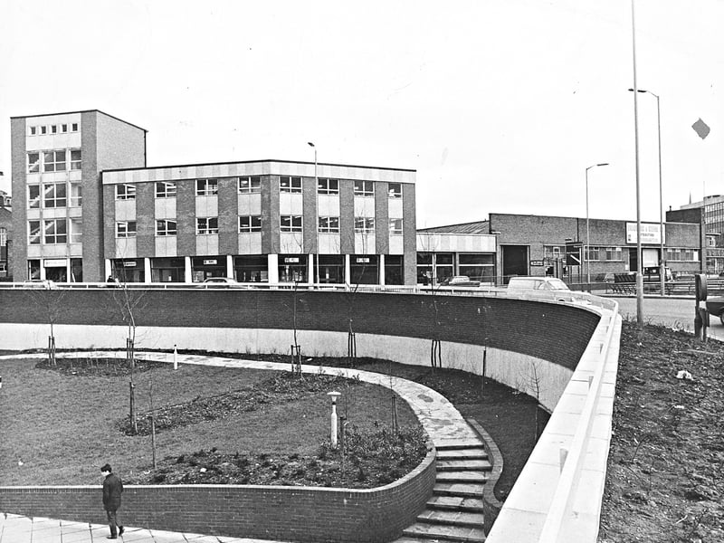 A solitary pedestrian walks past the newly completed sunken garden features bordering Wolverhampton's expanding ring road system in March 1969. Standing prominently in the background are the modern premises of Bradburn & Wedge, the well-known local motor dealership and garage. The striking contrast between the landscaped pedestrian subways and the sleek, 1960s commercial architecture highlights the extensive modernisation reshaping the town centre's urban layout during this era. Do you remember buying a car from Bradburn & Wedge or walking through these sunken ring road gardens back in 1969?