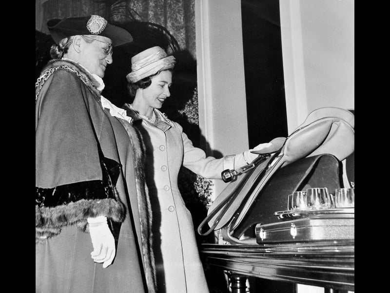 Queen Elizabeth II smiles as she inspects a collection of locally crafted presents during her royal visit to Walsall on May 24, 1962. The Mayor of Walsall, Councillor Mrs A. M. M. Taylor, presented the Monarch with fine leather goods and gifts chosen for both herself and the young royal children. Showcasing Walsall's famous international reputation for master leathercraft and trade craftsmanship, the civic presentation stood out as a proud highlight of the historic Black Country tour. Do you remember what gifts Walsall presented to the Queen or the buzz around town during her 1962 visit?