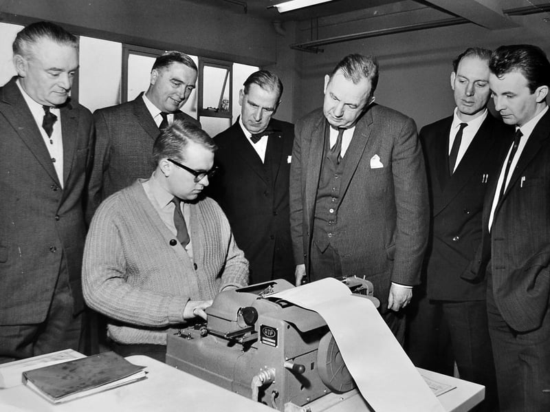 Mr W. J. Webb (far left), editor of the Walsall Observer, joins fellow regional newsmen to inspect revolutionary printing technology on December 7, 1964. Visiting the newly opened Shropshire Star office at Ketley, the delegation watched an operator use an A.T.F. keyboard to produce tape for photo units—a key step in pioneering web offset evening newspaper production. Representing Walsall's long-running local paper, Mr Webb looked on as modern electronic typesetting began to transform traditional hot-metal print rooms across the West Midlands. Did you use to buy a weekly paper every Friday to check the local headlines and sport?