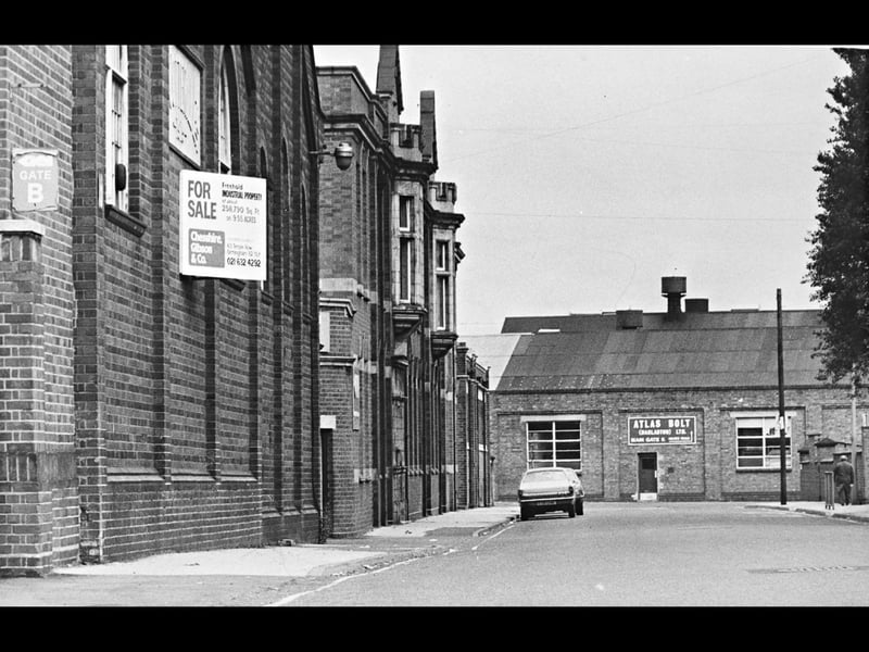 A prominent 'For Sale' sign hangs on the red-brick facade of GKN's main office block in Darlaston during an era of industrial transition. In the background across the street, the premises of Atlas Bolt (Darlaston) Ltd remain visible, grounding the streetscape in the town's long-standing reputation as the world's leading center for nut and bolt manufacturing. Once a sprawling hub of activity employing thousands, the site captured a moment of change for Guest, Keen and Nettlefolds and the surrounding Black Country industrial landscape. Did you or a family member work at GKN or any of the neighbouring bolt works in Darlaston?