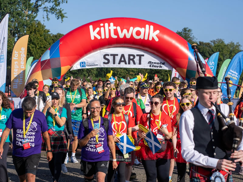 The kiltwalkers head off from Holyrood Park let by a bagpiper in the Edinburgh sunshine.