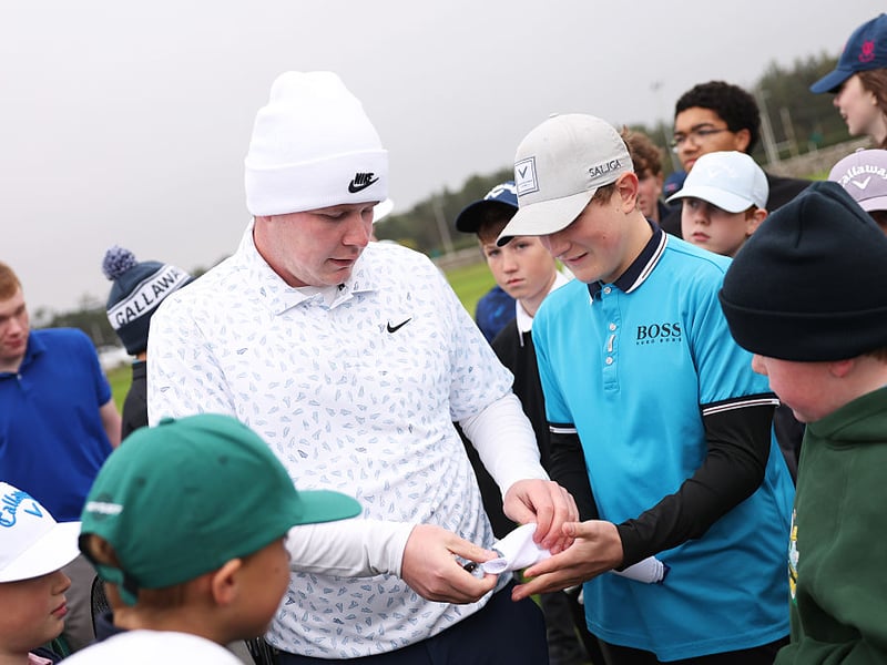 Robert MacIntyre signs autographs for young fans.