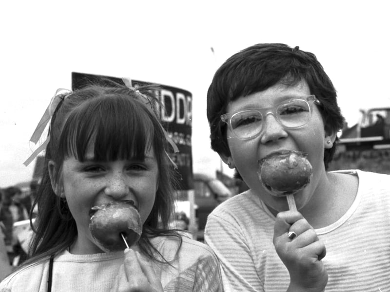 Two little girls enjoying toffee apples during the Craigmillar festival, Edinburgh, June 1984.