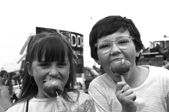Two little girls enjoying toffee apples during the Craigmillar festival, Edinburgh, June 1984.
