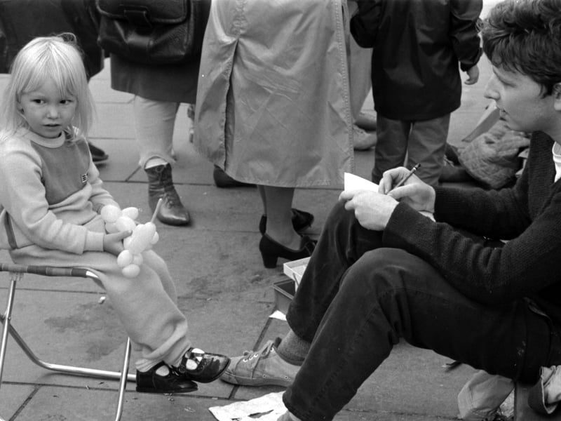 A little girl has her portrait drawn by a street artist during Edinburgh Festival 1985.