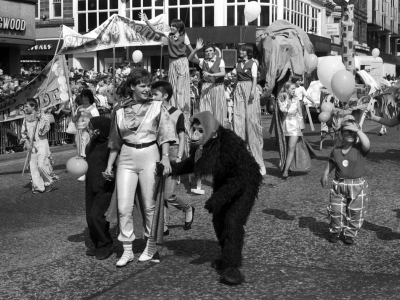 Monkey suited children and stilt walkers make their way past crowds on Princes Street in the Festival Cavalcade, August 1984