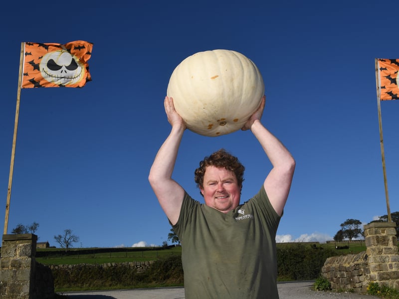 Farmer Tom Whitley standing proudly at the entrance to the farm with one of his giant pumpkins