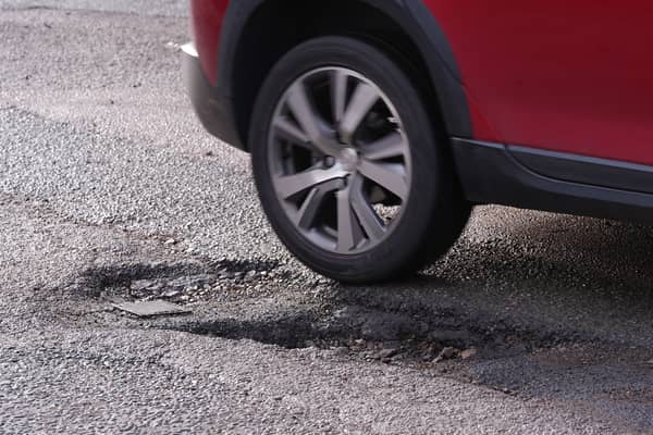 A car drives past a pothole on a road