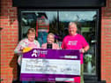 Ivan and Sylvia Kerr pictured outside Storey Menswear, Linen Green, with their cheque for £20,049.74. 
