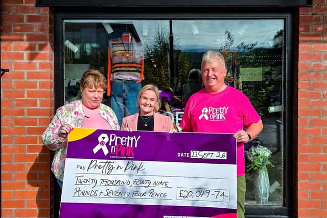 Ivan and Sylvia Kerr pictured outside Storey Menswear, Linen Green, with their cheque for £20,049.74.