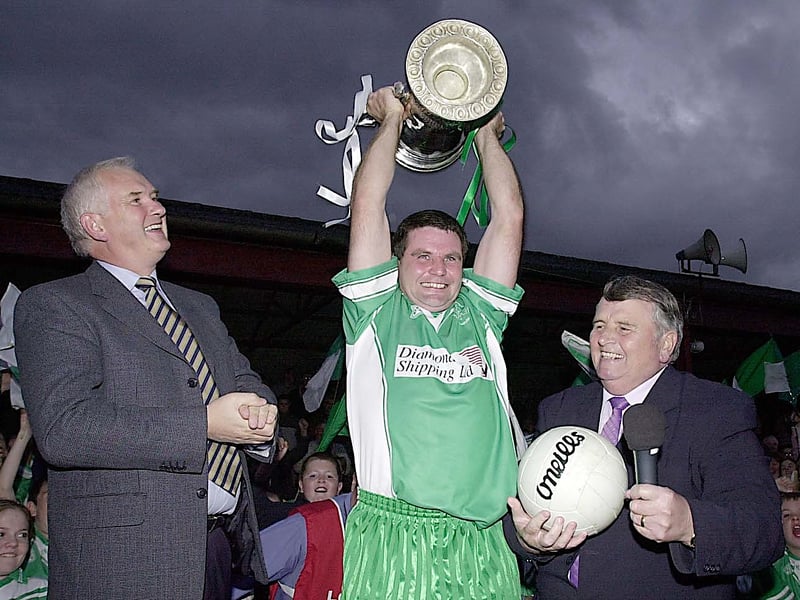 Seán White raises the Joe Ward Cup as he is watched by Oliver Murphy (Lampost Construction) and Paddy McMahon (LCB Chairman)