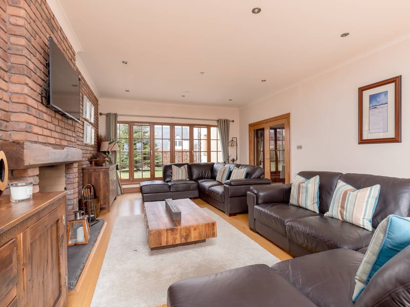 The East Lothian property's impressive sitting room, with a central fireplace and French doors opening directly onto the garden.