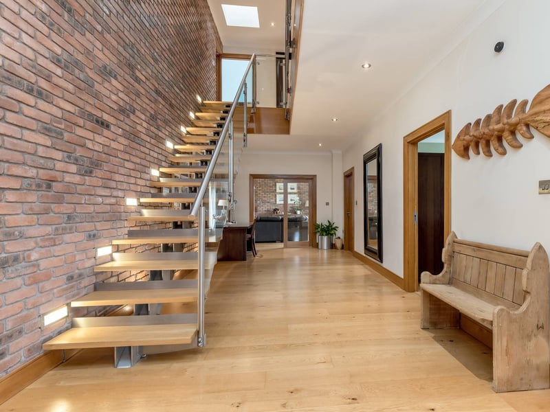 The entrance vestibule opens into this broad central reception hall with a feature staircase rising to the upper floors.
