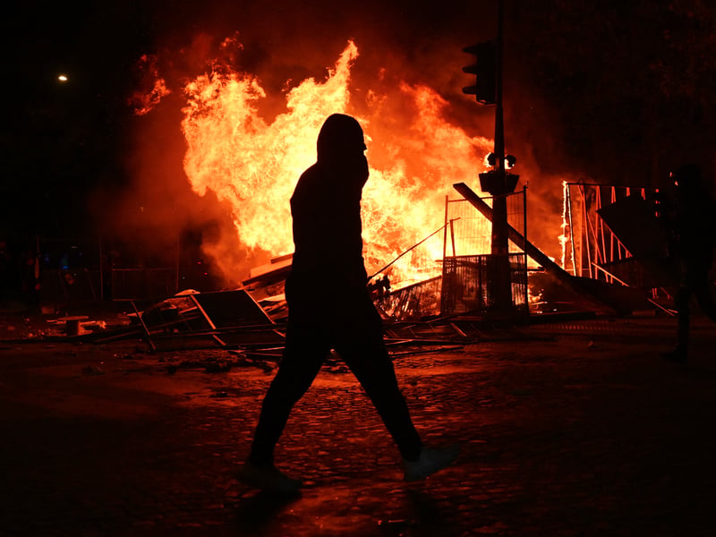 A demonstrator walks past a fire on Boulevard Haussmann