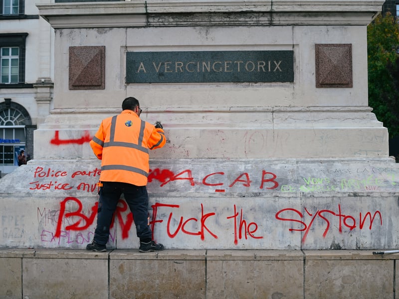 A man cleans graffiti on the statue of Vercingetorix on Place de Jaude in Clermont-Ferrand.