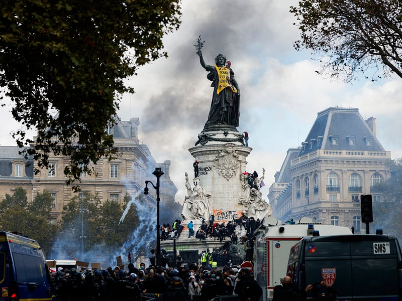 Smoke rises as the 'Statue de la Republique' is covered with a bannner reading "2026, the police are mutilating high school students"