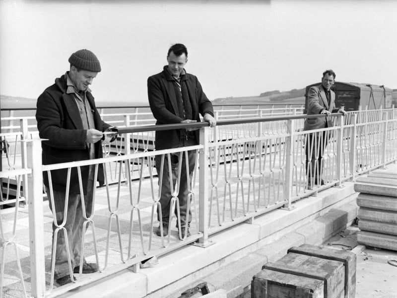 Workmen fixing railings to bridge central walkway