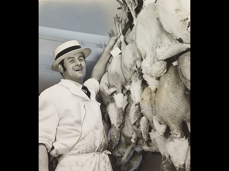Wearing a traditional straw boater hat, white apron, and tie, butcher Roger Denny smiles as he checks a wall of hanging turkeys in Cheslyn Hay on December 21, 1970. Despite regional concerns over outbreaks of fowl pest that year, Roger reassured local customers that their Christmas dinners were safe and ready for the annual festive rush. The festive scene captures the busy, personal touch of neighbourhood butcher shops that were essential to preparing family feasts every December. Do you remember queueing up at your local butcher shop to collect the festive turkey or roast in the lead-up to Christmas? What were your family’s favourite holiday food traditions back in the 1970s?