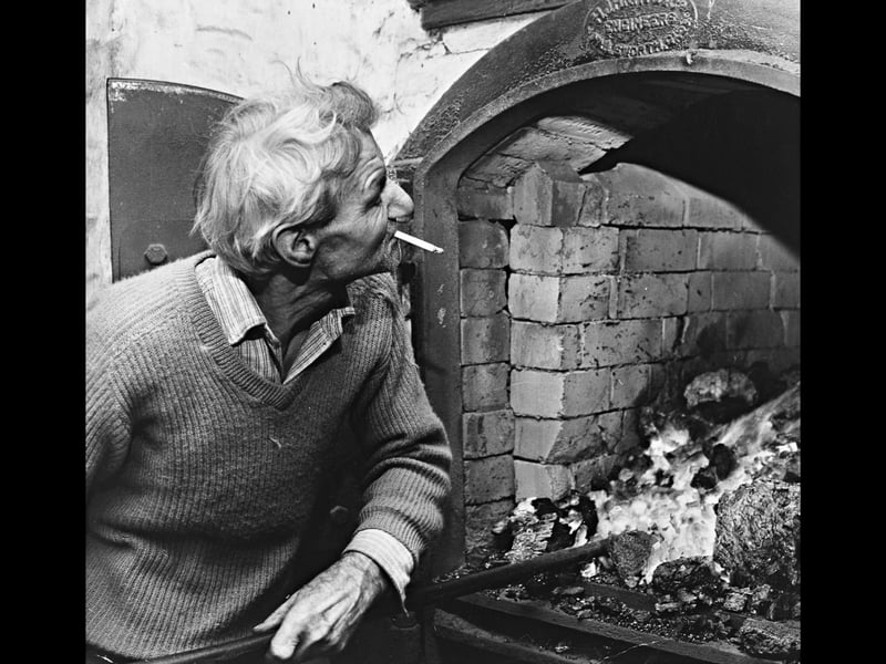 With a cigarette resting between his lips, Will Chambers tends to the glowing coal fire heating the kilns at Frederick Law & Son's maltings in Wombourne on November 11, 1970. Malting was a relentless, seven-day-a-week commitment that required constant care to maintain precise temperatures for germinating and drying barley. Leaning casually against the heavy iron furnace doors, Will reflects the grit, patience, and traditional craftsmanship that powered the region's brewing trades long before modern automation took over. Do you remember seeing the old maltings or local breweries operating across Wombourne and the surrounding areas in the 1970s? Did anyone in your family work in traditional trades like malting, brewing, or furnace stoking?