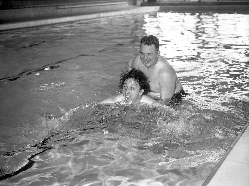 A proper aquatic task! On March 10, 1961, cross-channel swimmer Bill Pickering, from Bloxwich, takes comedian Ken Dodd through his paces in the pool. Bill made the journey from his home twice a week to give Ken swimming lessons in Coventry ahead of his summer season, helping the star upgrade from paddling to proper ocean swimming. Supporting a splashing and wide-eyed Ken in the water, the record-breaking swimmer showed immense patience as he traded open-water training for pure comedic chaos.
