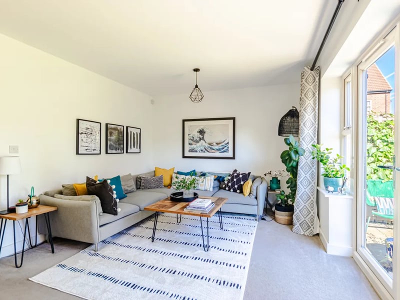 The inviting lounge, a bright and comfortable living space with patio doors opening directly onto the garden, framing the pleasant green outlook.