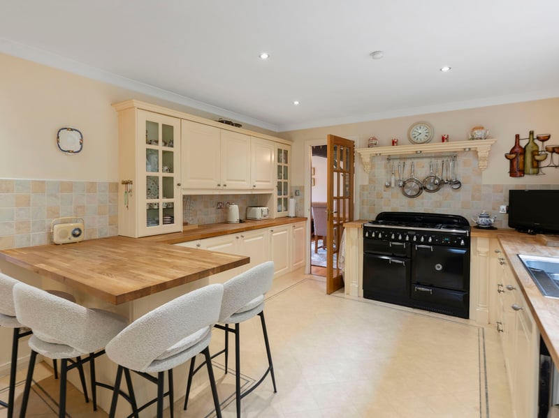 The breakfasting kitchen is cleverly designed to provide a generous range of cream coloured cabinets alongside expansive wooden worktops with a breakfast bar return. Splashback tiles complement the look adding texture to the neutral backdrop, altogether creating a lovely setting for quick meals and morning coffee.