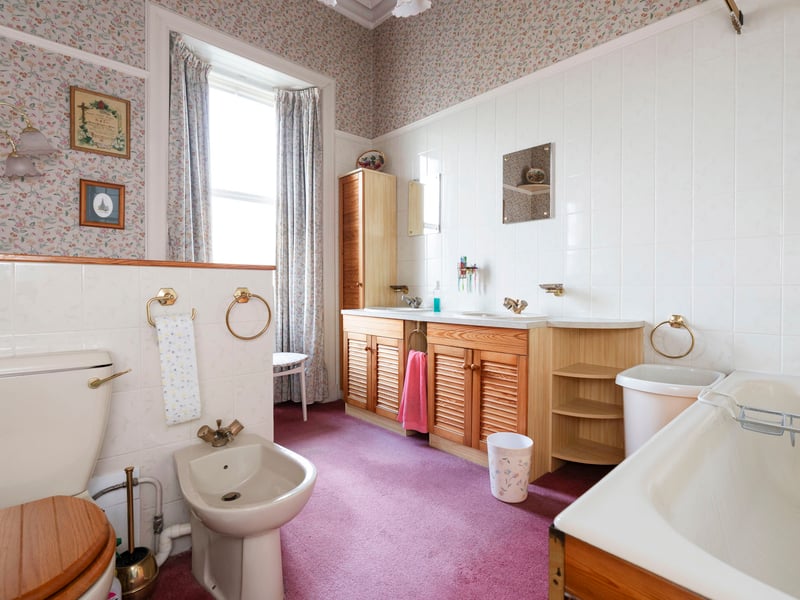 An archway flows into a spacious en-suite bathroom with a bath, separate shower enclosure, bidet, WC, and twin washbasins set within generous vanity storage.