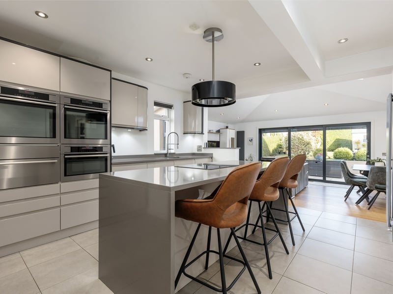 The contemporary kitchen is fitted with an excellent range of sleek wall and base units, complemented by Silestone worktops and a breakfast bar. High quality appliances include an induction hob, two ovens, one incorporating a warming drawer, providing everything required for modern family living.