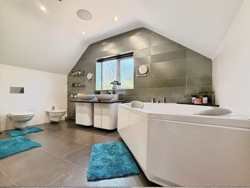 A magnificent luxury family bathroom featuring a circular Jacuzzi bath, large walk-in shower with mains-fed waterfall shower and separate shower attachment.
