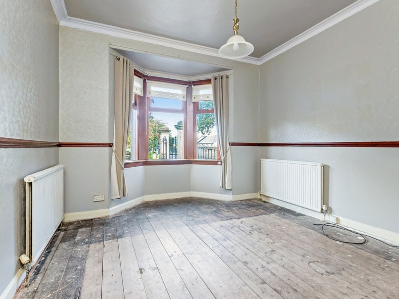 The spacious living room, featuring an attractive bay window, feature fireplace and timber flooring.
