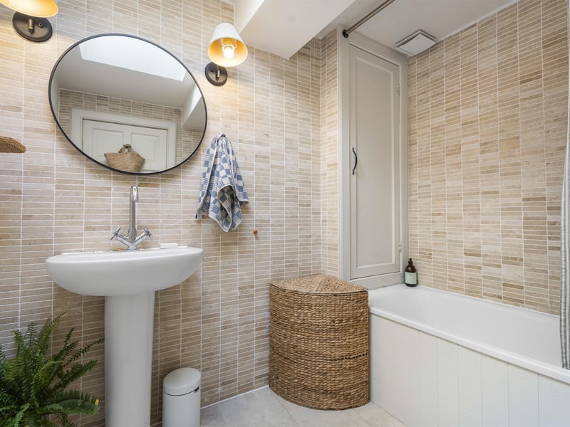 The beautifully bright family bathroom, complete with shower over the bath and an integrated storage cupboard.