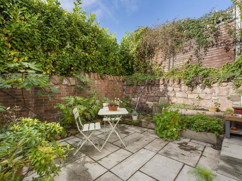 Outside, the low-maintenance courtyard garden features a patio bordered by mature plants and shrubs, including a lovely fig plant. Ample on-street parking is available, while an energy-efficient air-source heat pump provides heating.