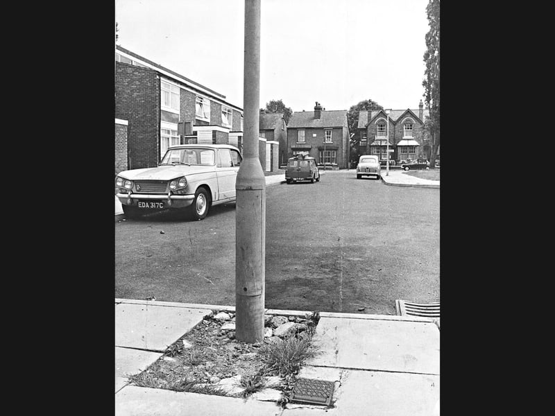 A Triumph Vitesse and other classic 1960s vehicles sit parked along St Edmunds Close, Wolverhampton, in July 1966. Modern housing developments stand alongside older brick homes in the background, framing a serene, everyday residential view from the town during the mid-60s. Do you remember living in or visiting St Edmunds Close around this time?