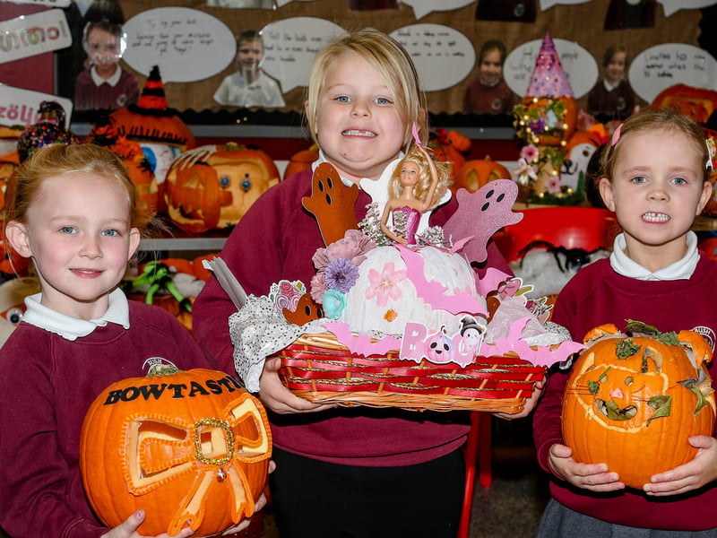 P2 pupils, Auguste, Bonnie and Maisie, showing off their pumpkins. AM264410