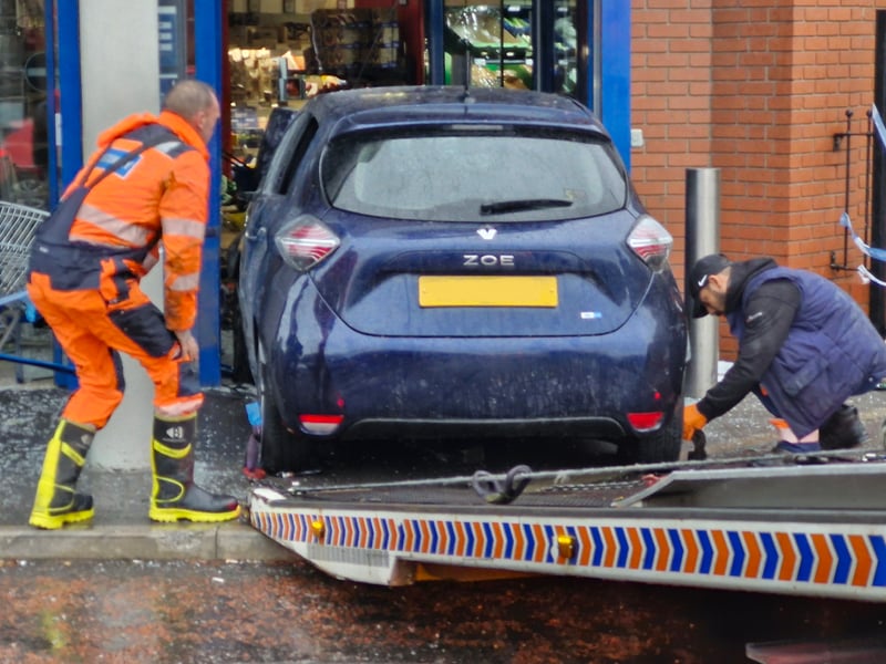 The car is secured by the recovery team after being removed from the store