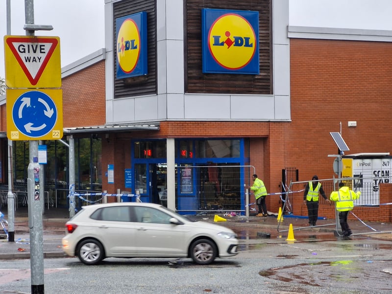 Security crews work to fence off the entrance to Lidl after the car was removed