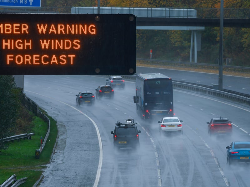 Cars pass under a gantry warning sign on the M8 as the Met Office has issued an Amber weather warning