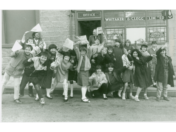 Local school children await the arrival of the Royal visitors (Prince Charles and Princess Diana) outside Whitaker & Clegg Builders' Merchants in 1986, later it became Burnley Building Supplies on Hammerton Street.