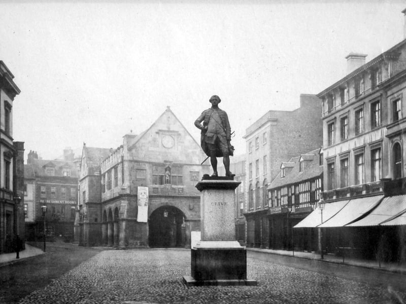 A statue of Clive of India stands proud as the focus of the cobbled Square in Shrewsbury. It was unveiled in 1860. On the left is the 1834 Shirehall built to a design by Sir Robert Smirke. Beyond the statue is the ancient market hall with a banner or poster hanging from it, and behind that are Shrewsbury refreshment rooms, according to a sign on the building. It looks a deserted scene, but that's misleading, as people moving about will have been turned into ghostly blurs.