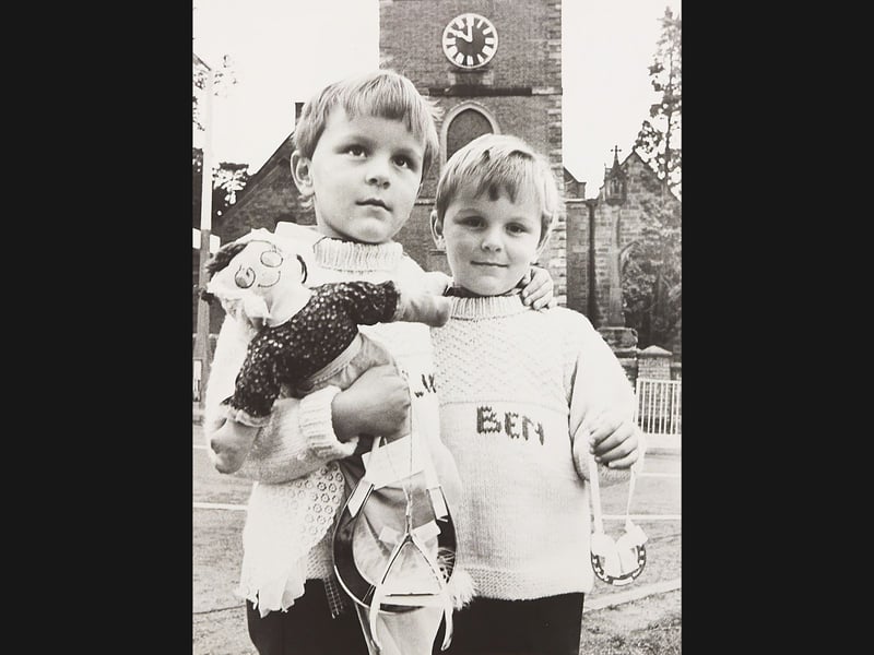 Knitted jumpers, miniature lucky horseshoes, and a beloved cloth doll, this September 1982 photograph captures four year old identical twins Luke and Benjamin Rich standing outside St Bartholomew's Church in Penn. Absolutely fascinated by weddings, the young brothers from nearby Manor Close spent weekends waiting outside the historic church hoping to be invited as pageboys for passing wedding parties. With the distinctive church clock tower rising behind them, their knitted outfits, including Ben with his name proudly stitched across his chest, created an endearing local human interest tale for Wolverhampton readers. Do you remember seeing the Rich twins waiting outside St Bartholomew's Church hoping for a glimpse of the bride and groom? Who recalls being part of a festive wedding celebration in Penn around the autumn of 1982?