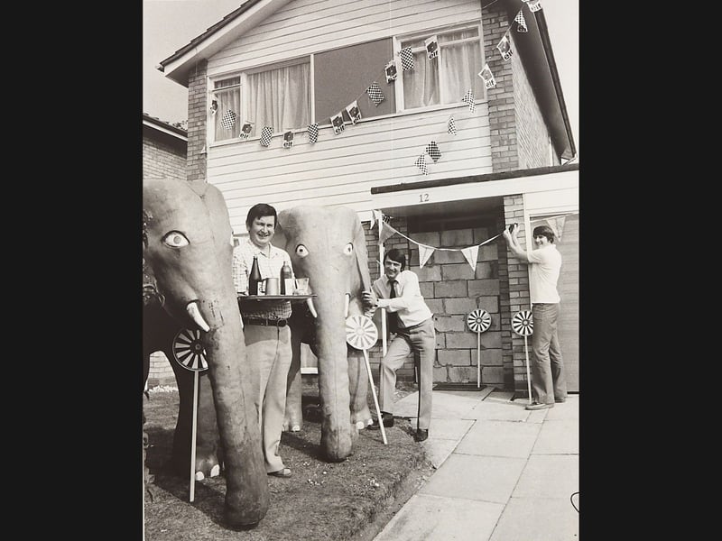 Tettenhall Round Table chairman Bob Archer, prank organiser Peter Barnsley, and Tony Jones add the finishing touches to a lavish practical joke outside number 12 Glendale Close, off Castlefort Road, Wolverhampton, in September 1982. Preparing a surreal welcome for newlywed solicitor Dave Bruce and his bride Alison returning from their Portuguese honeymoon, his colleagues adorned the front garden with bunting, pinwheels, two life-size papier-mâché elephants, and a lightly cemented brick wall blocking the front door. Do you remember the hilarious stir caused by the elephants on Castlefort Road back in the autumn of 1982?