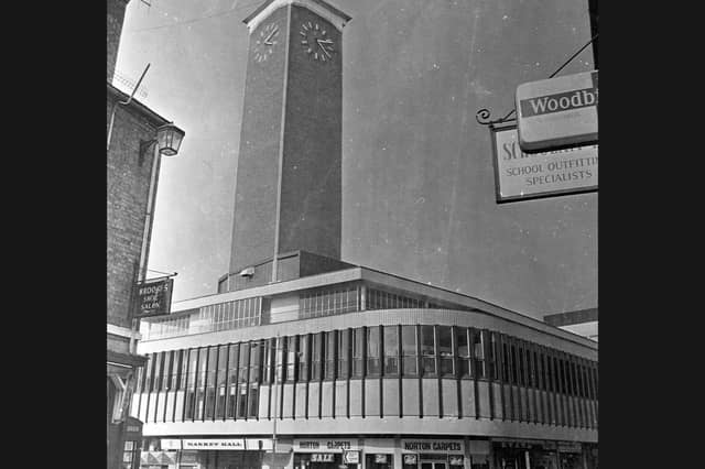 The distinctive '60s architecture of the Shrewsbury Market Hall and its soaring Mardol clock tower dominate the street corner in 1979, framed by familiar shopfront signs for local businesses like Brooks Shoe Salon and Norton Carpets in a photograph captured by Walter Winder. Do you remember when the clock tower and modern market building were a relatively fresh addition to the Shrewsbury skyline? Which shops along Bellstone, Shoplatch, or inside the Market Hall itself did you visit most often during those years?
