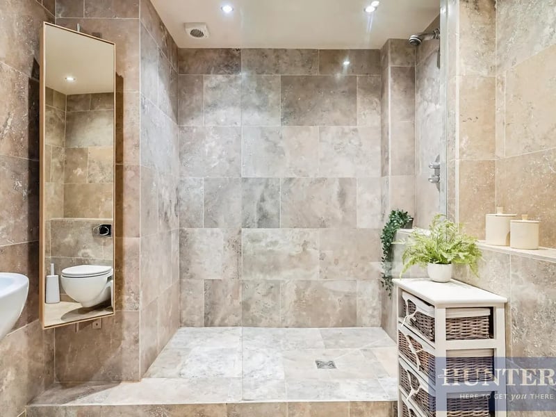 The luxurious ground floor bathroom, benefitting from underfloor heating and sleek modern tiling. 