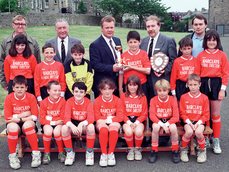 The Fort Primary football team show off their new strip in July, 1992, while David Hendry, from the sponsors Barclays Funeral Directors, presents the school's player of the year with his award.