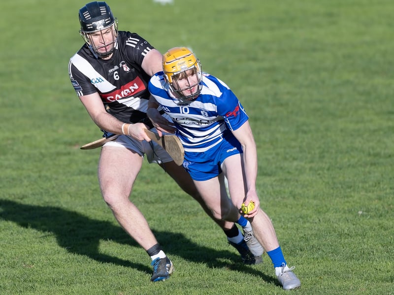 Naas wing forward Oisin O'Neill holds off the tackling Cathal McCabe Maynooth before laying off his hand pass