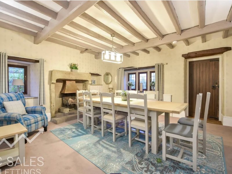 The elegant dining room has a stone fireplace and exposed beams.