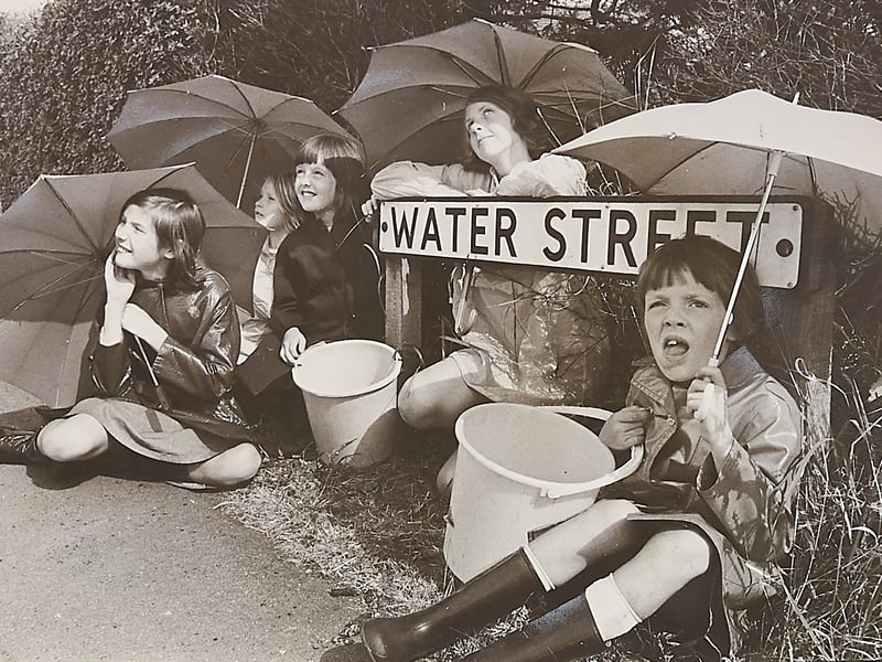 Armed with umbrellas and empty buckets, youngsters Lindsy Fisher, Elizabeth Heath, Susan Fisher, Christine Heath, and Sharon Fisher sit hopefully beneath the street sign on Water Street in Chase Terrace, Burntwood, in August 1976. During one of the most punishing droughts in modern British memory, living on an aptly named thoroughfare prompted plenty of good-humoured local banter as families looked skyward for any sign of a downpour to break the relentless heatwave. Do you remember coping with the scorching summer drought or waiting for the rain to return across Staffordshire in August 1976?