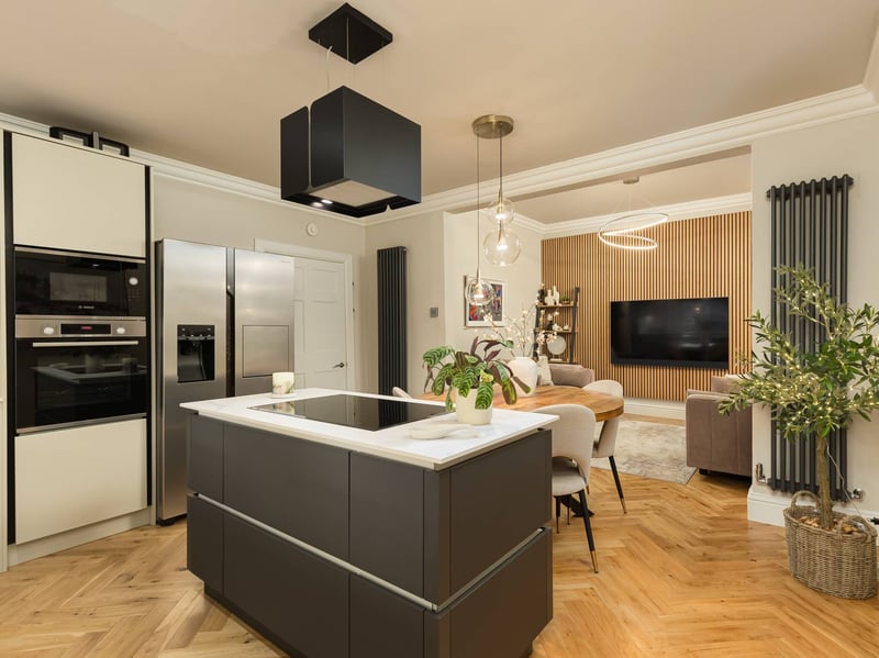 The sleek contemporary kitchen is centred around a large island. Handleless wall and base-mounted cabinetry incorporates a Bosch induction hob, oven, extractor hood, microwave and dishwasher, alongside a wine fridge and freestanding American-style fridge/freezer. A separate utility room, conveniently located off the kitchen, houses the washing machine and tumble dryer.