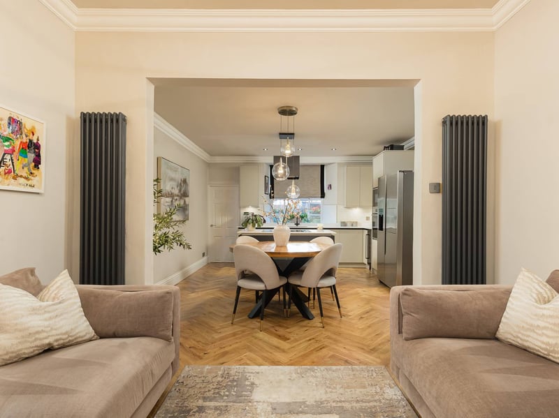 Generously proportioned, this inviting space, with a sophisticated wood panel feature wall, offers a comfortable area for relaxing alongside ample room for a good-sized dining table and chairs.
