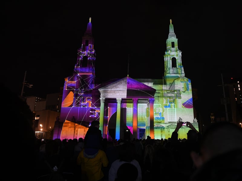 A light show lights up Civic Hall as crowds watch from Millennium Square.